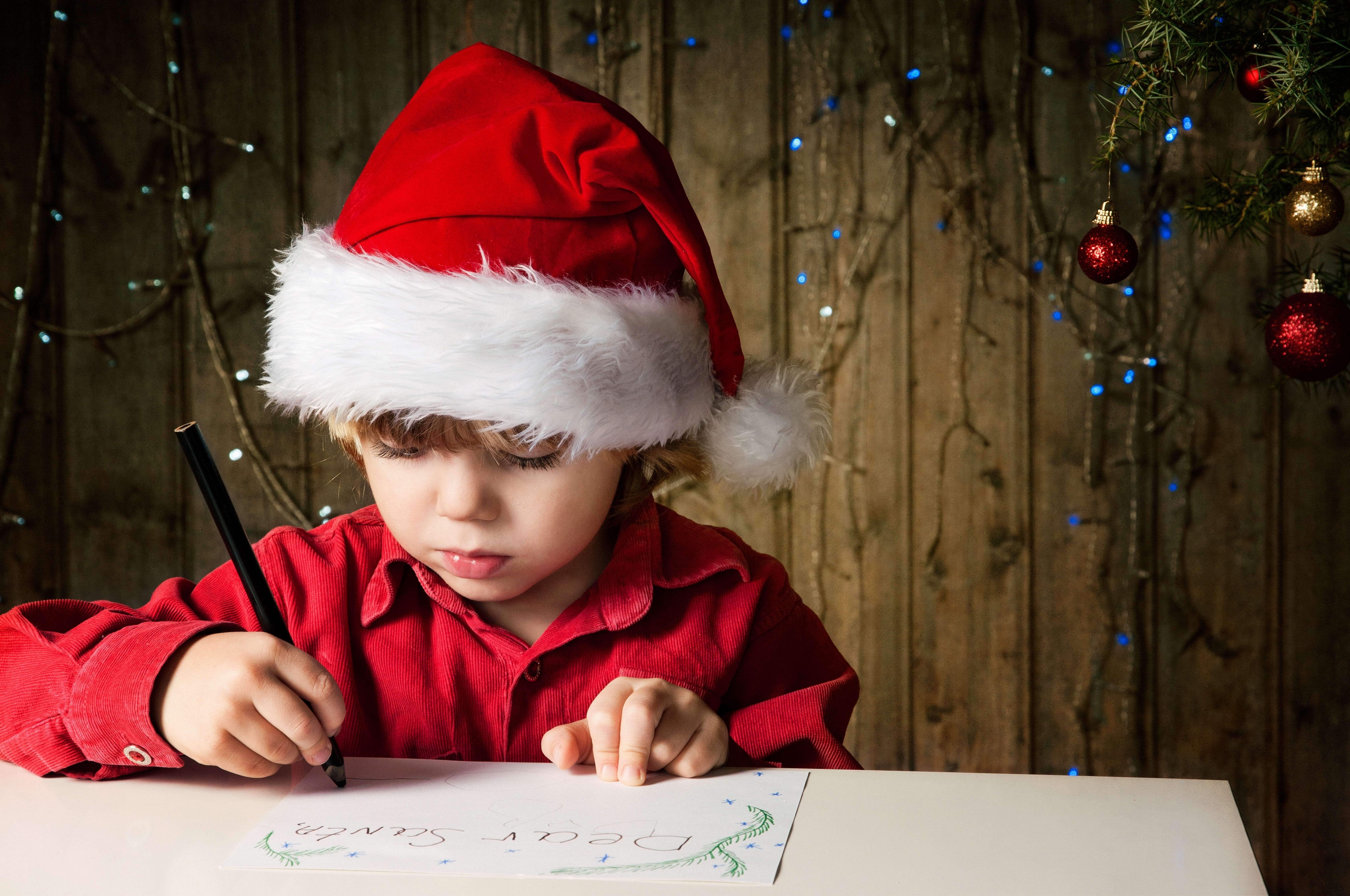 Отправить дед мороз. Новый год дети. Ребенок пишет письмо деду Морозу. Новогодний мальчик. Мальчик в новогодней шапке.