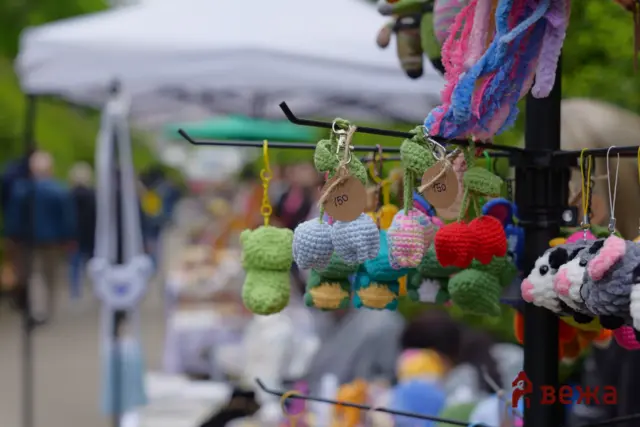 Row of colorful crocheted plush keychains with price tags hanging at an outdoor market stall.