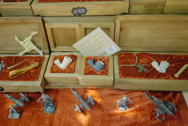 Wooden display case with red velvet inserts holding gray sci‑fi spaceship models and price tags, plus a flyer resting on top.