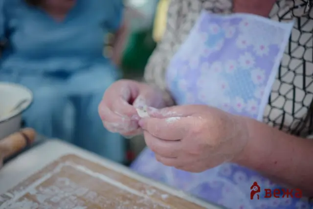 Close-up of hands kneading dough on a floured wooden surface.