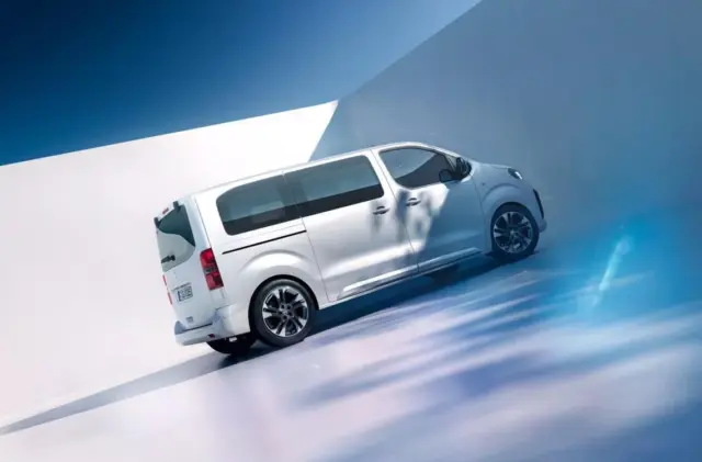 White van angled on a glossy blue studio backdrop, conveying motion and speed in a stylized setting.