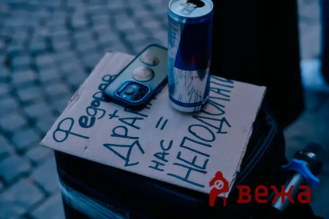 Close-up of a Red Bull energy drink can on a handwritten cardboard box, with a smartphone nearby.