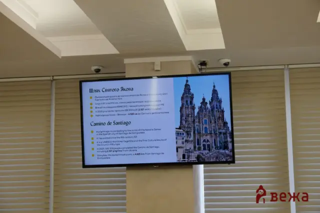 Digital display board with information about Camino de Santiago, featuring a cathedral image on the right.